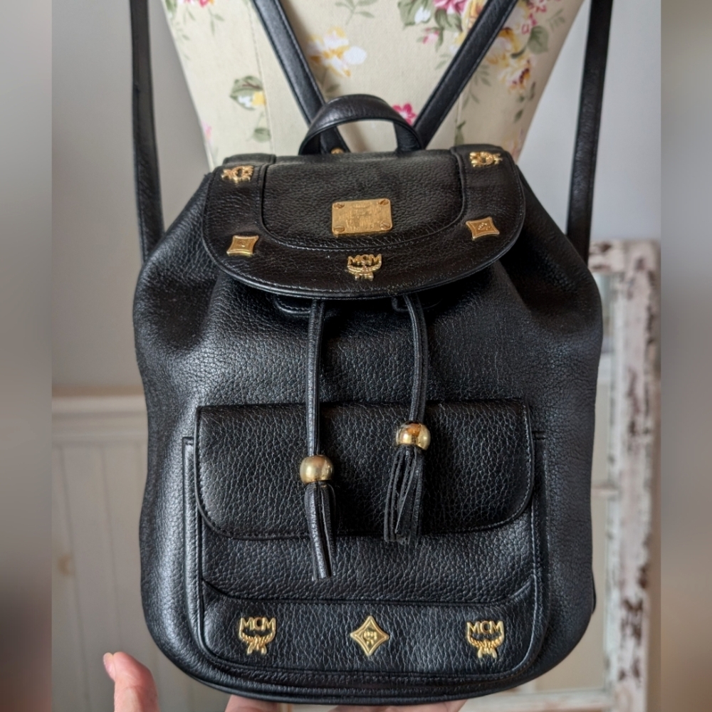 MCM black backpack with golden studded logo motifs and‎ drawstrings.